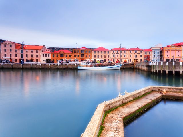 Sullivan's cove of Hobart harbour with historic fishing boat in front of heritage houses on city waterfront.