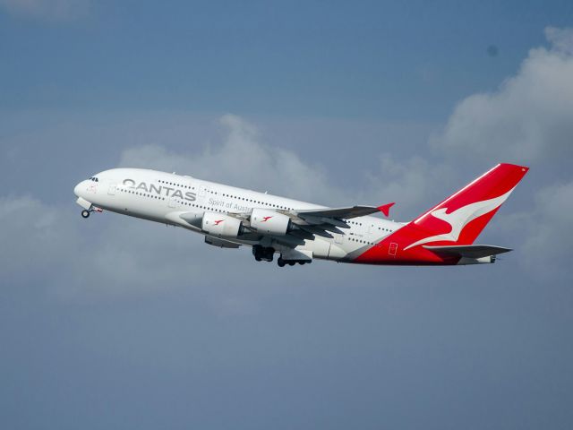 Qantas plane flying in front of clouds