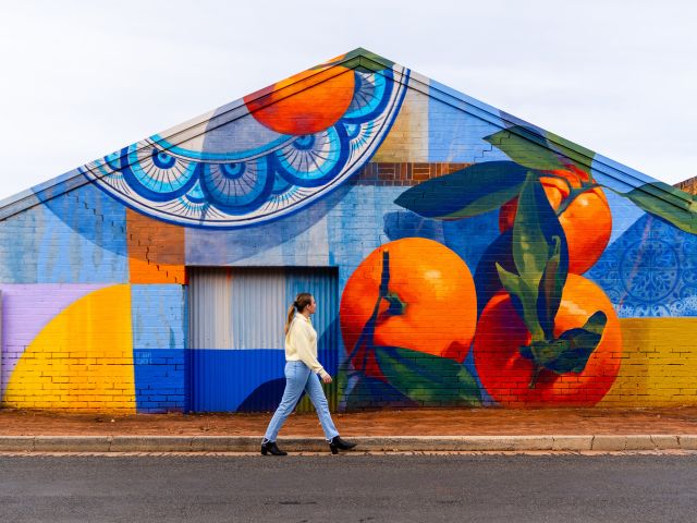 A woman walking past a food mural, something you can spot during A Taste of Italy Griffith.