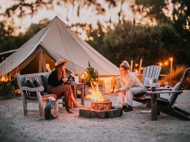 Guests enjoying campfire by glamping tent