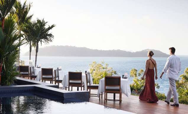 A couple standing at qualia, gazing out over the endless ocean horizon.