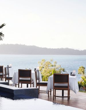 A couple standing at qualia, gazing out over the endless ocean horizon.