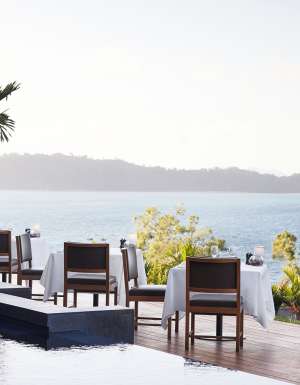 A couple standing at qualia, gazing out over the endless ocean horizon.