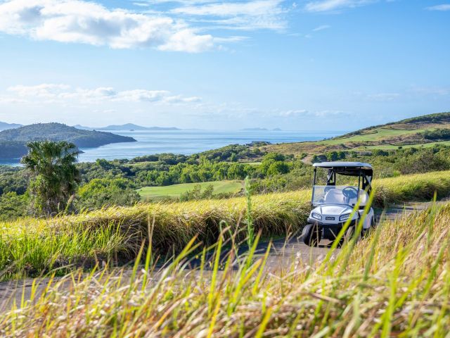 A buggy parked overlooking Hamilton Island’s golf course, with sweeping views of the sea at Whitsundays in winter.