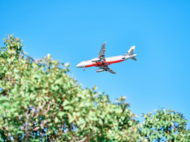 Jetstar airplane flies through a clear blue sky in Currumbin Beach, Gold Coast, Australia
