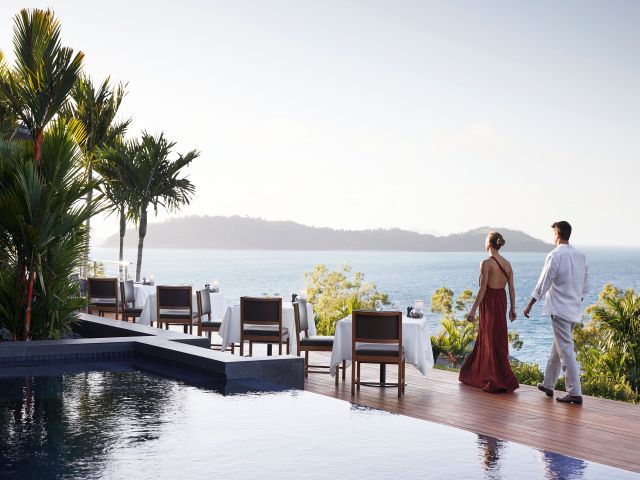 A couple standing at qualia, gazing out over the endless ocean horizon. 