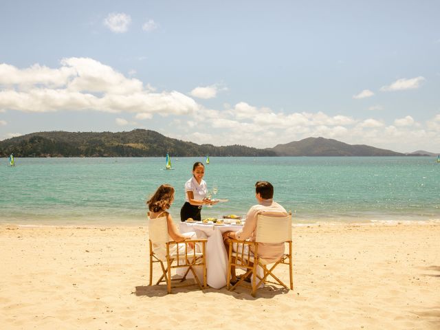 A romantic beachside lunch as champagne is served.