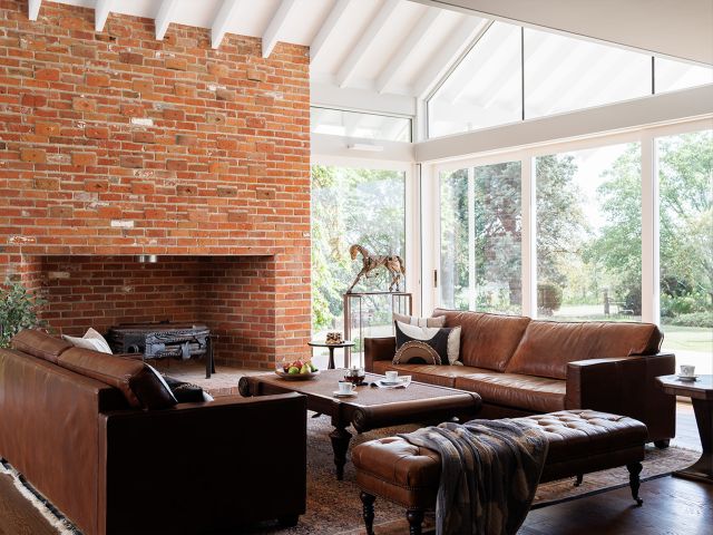 A living room with a brick fireplace and leather seating