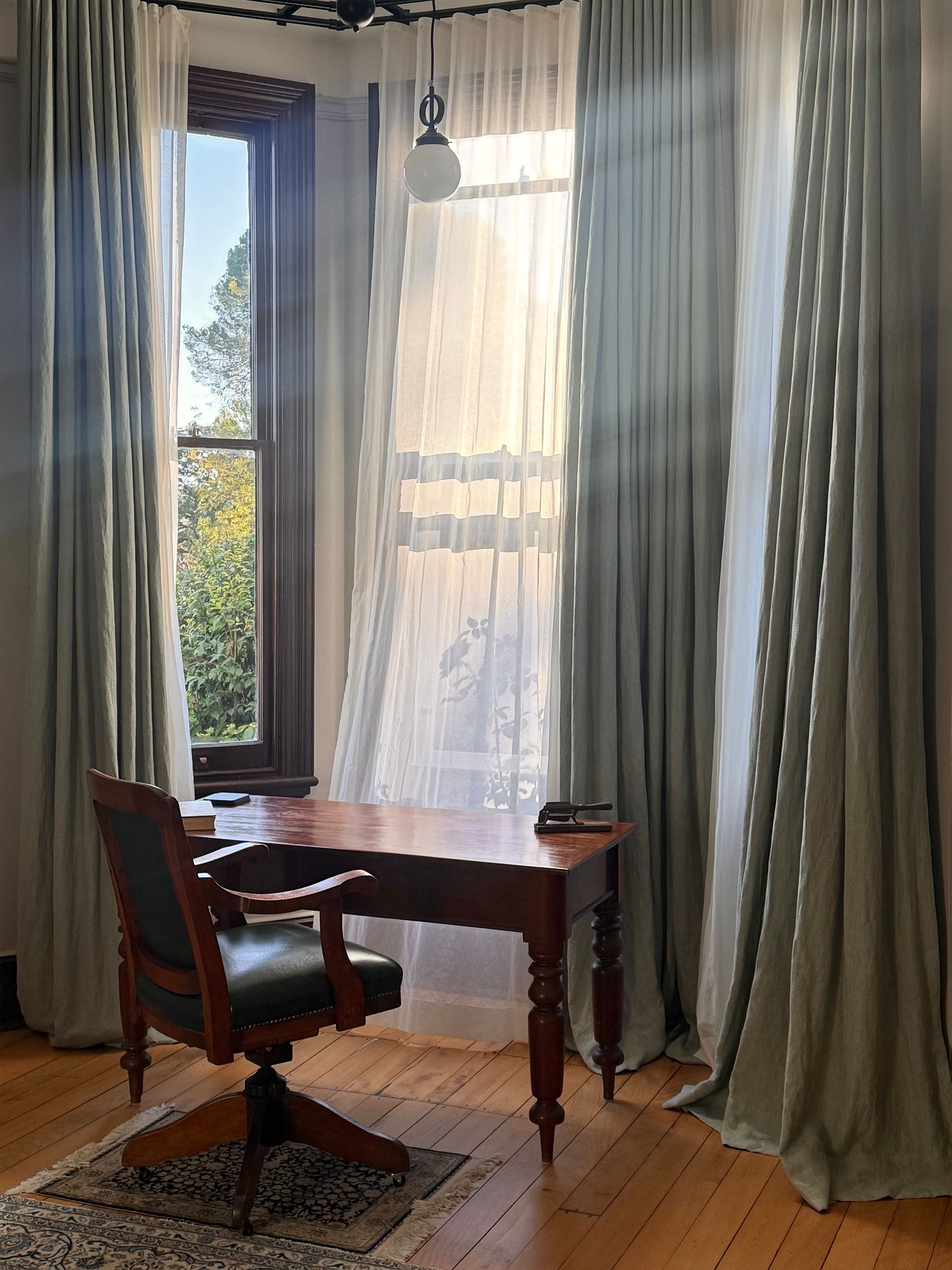Sunlight shining through sheer curtains onto a writing desk