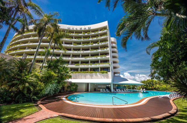 Hilton Cairns viewed from below, showcasing its tropical pool and resort-style surrounds.