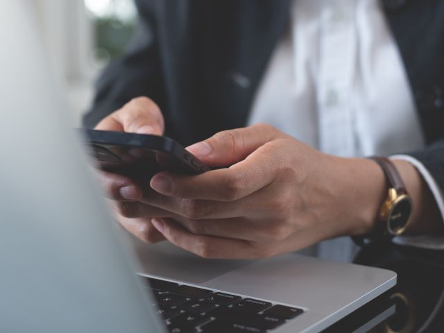 Woman holding phone in front of laptop