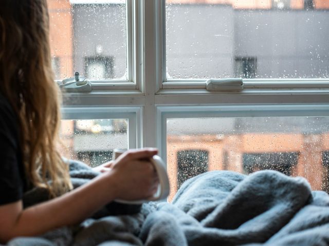 Girl enjoying a coffee in bed on a rainy day