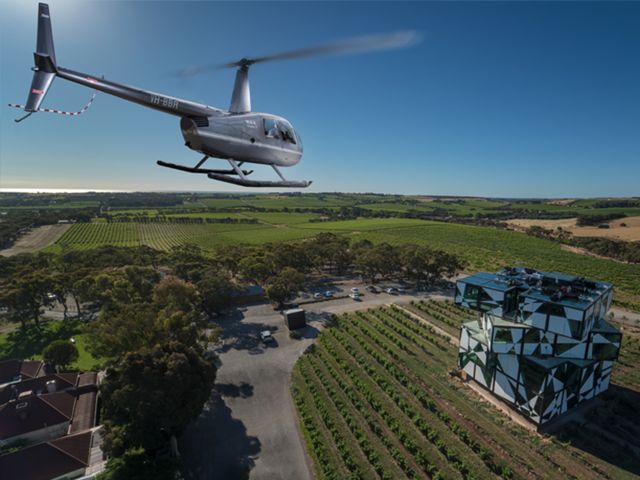 A helicopter flying above sprawling vineyards.