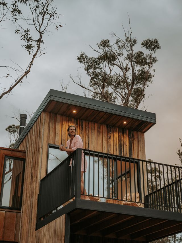 Woman on balcony of cabin at Arden Bathhouse