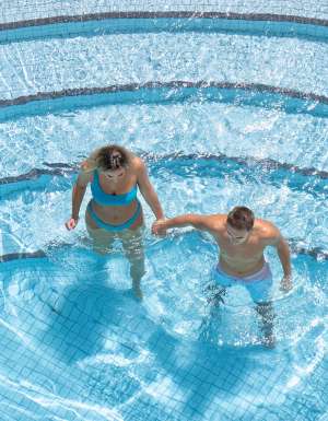 A man and a woman walking through the pool.