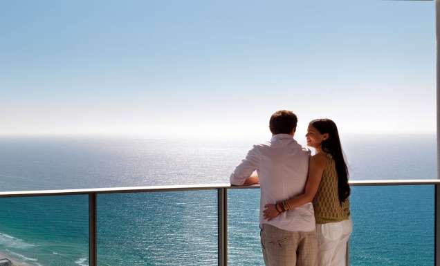 A couple standing on the balcony of Hilton Surfers Paradise, taking in the ocean views from their Deluxe Ocean View Residence.
