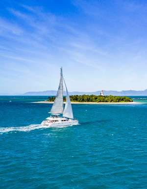 A sailboat gliding through crystal-clear turquoise seas.