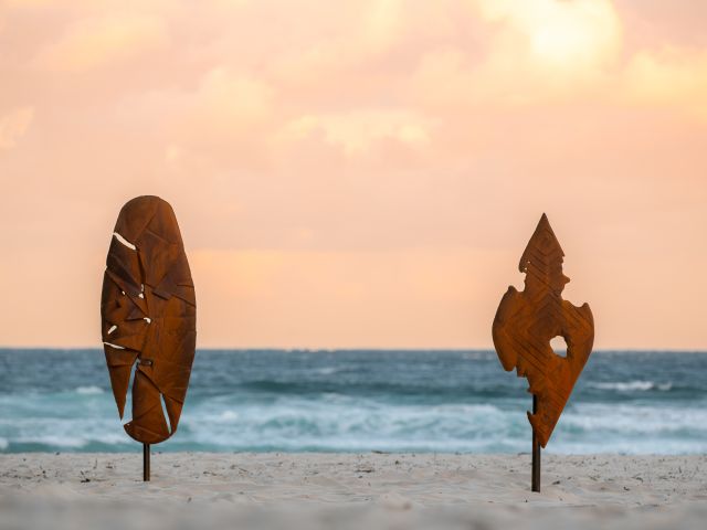 Two rust-coloured upright forms by David Doyle, Kaaku-Kaakulinya: Eternal Sentinels, on the sand at Sculpture by the Sea, Bondi