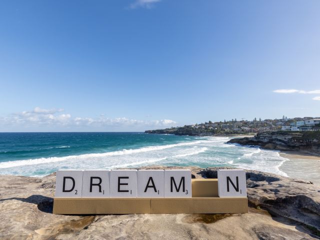Letter tiles spelling DREAM_N by Emma Anna on the rocks above Bondi Beach at Sculpture by the Sea