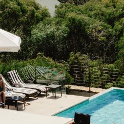 Two women enjoying drinks by the pool with ocean views.