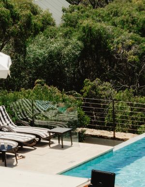 Two women enjoying drinks by the pool with ocean views.