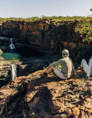 two people from outback spirit tour sit overlooking mitchell falls in the kimberley