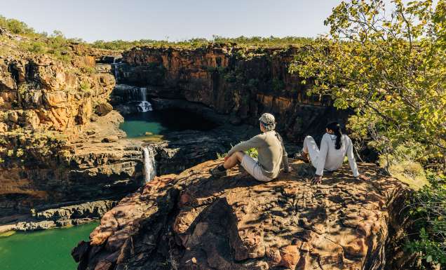 two people from outback spirit tour sit overlooking mitchell falls in the kimberley
