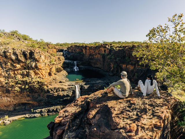 two people from outback spirit tour sit overlooking mitchell falls in the kimberley